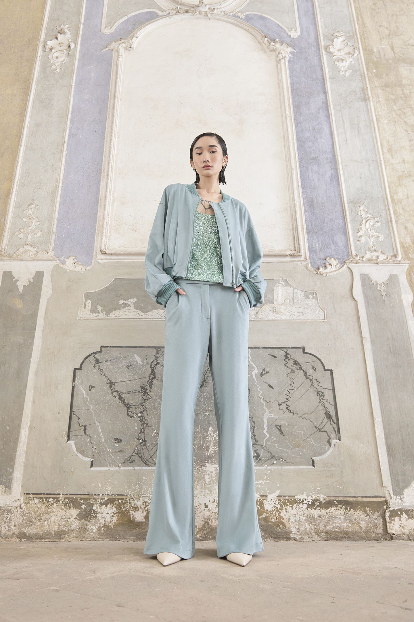 Una donna in abito blu è in piedi davanti a un edificio.