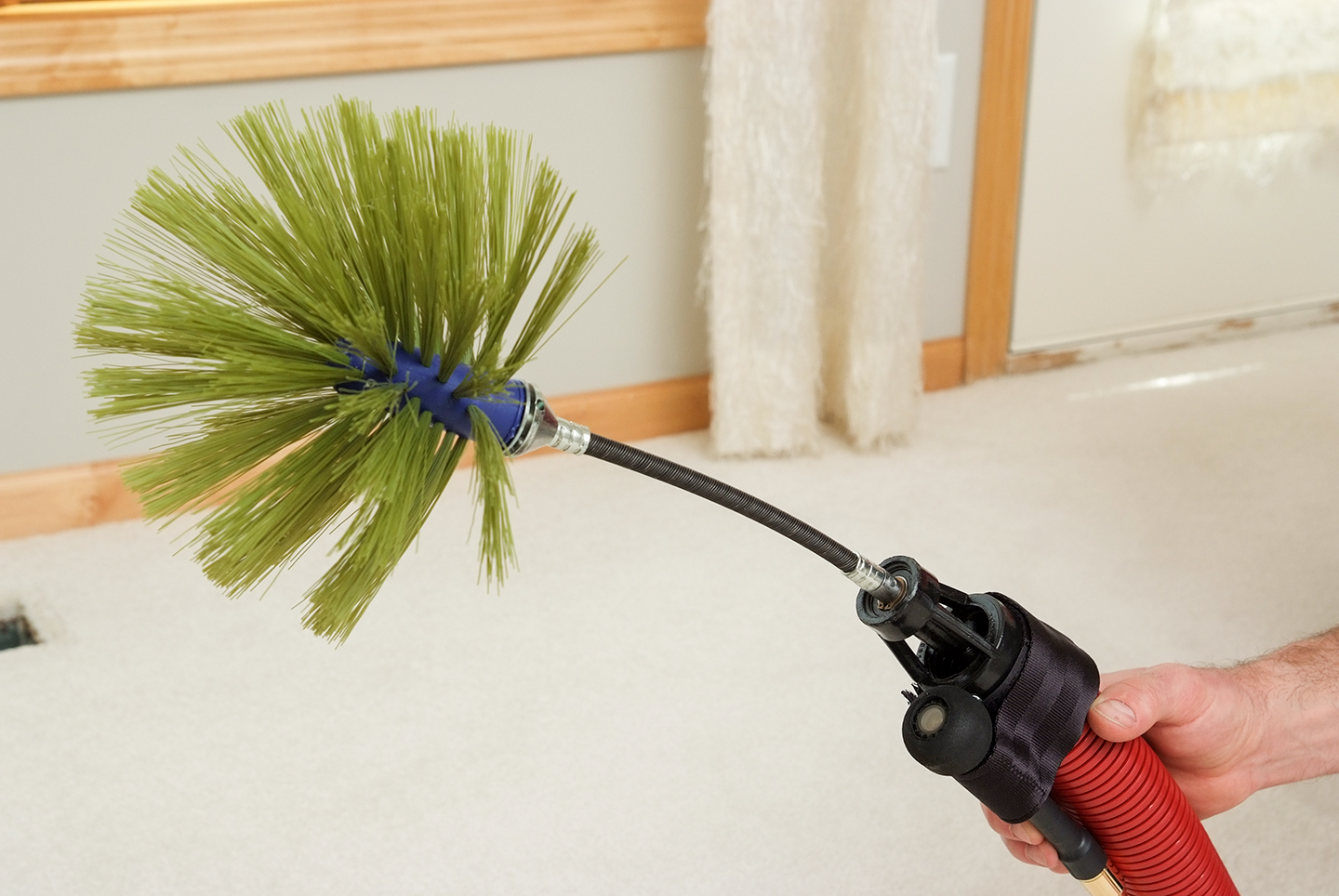 A person is holding a hose with a brush attached to it.