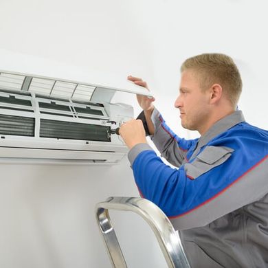 Technician repairing an air conditioner — Plumbing Services in Valparaiso, IN