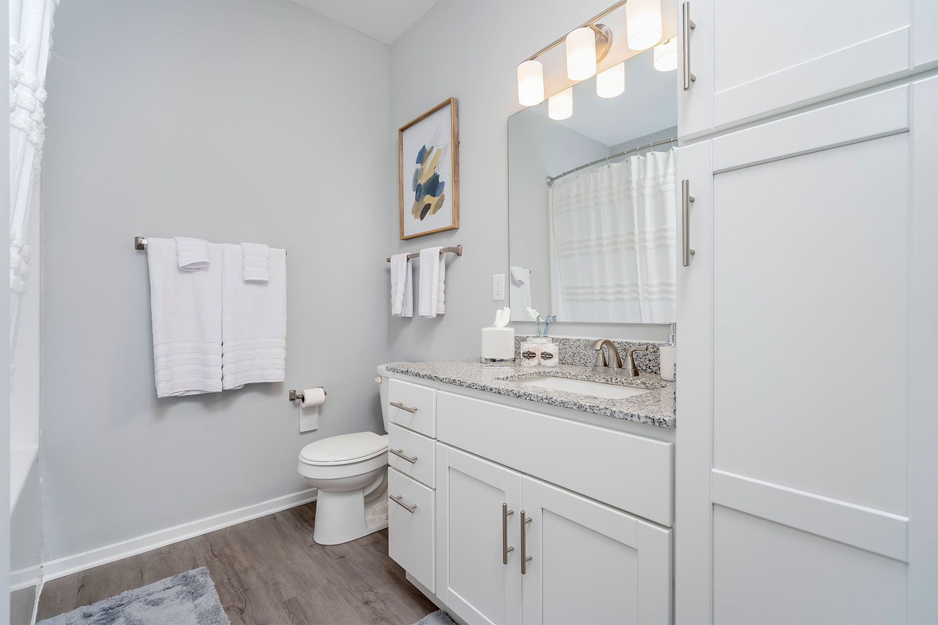 Bathroom with white vanity, granite countertop, large mirror, and towels.