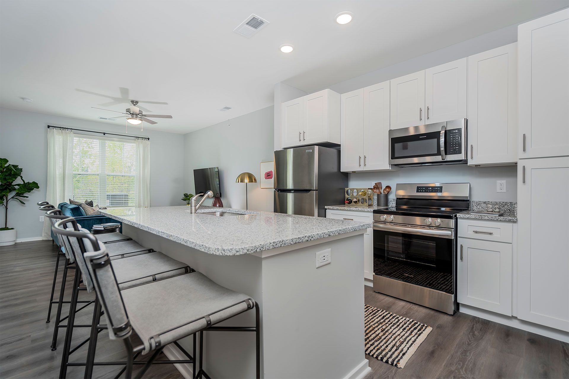 Modern kitchen with white cabinets, granite island, bar seating, and stainless appliances.