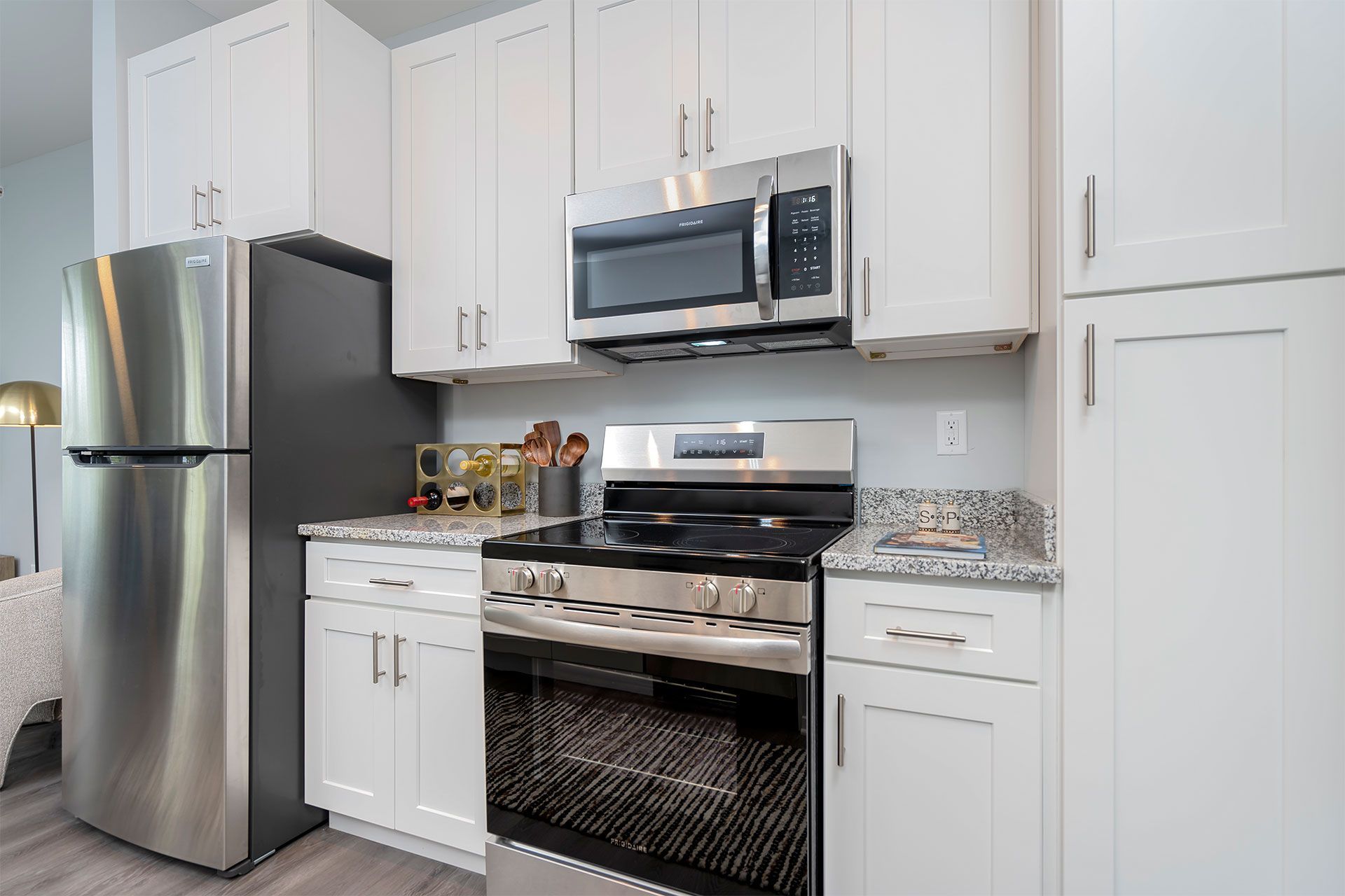 Modern apartment kitchen with stainless steel appliances, white cabinets, and granite countertops.