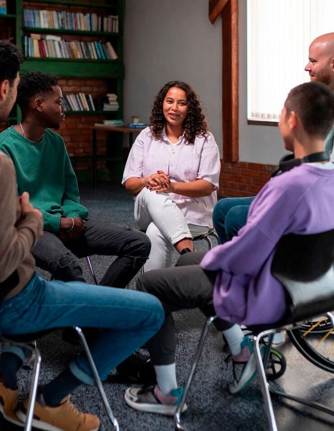 A group of people are sitting in a circle talking to each other.