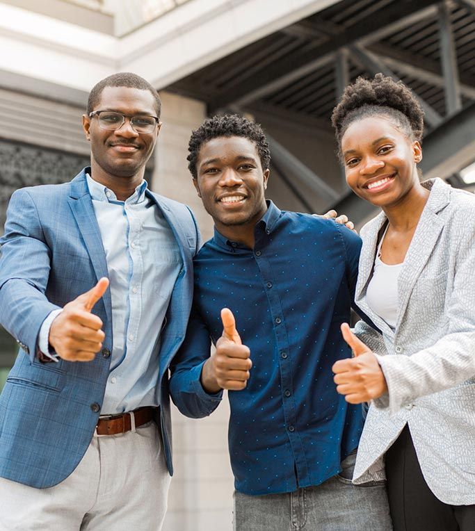 Three people are posing for a picture and giving a thumbs up