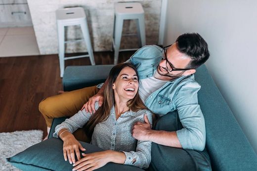 A man and a woman are laying on a couch in a living room.