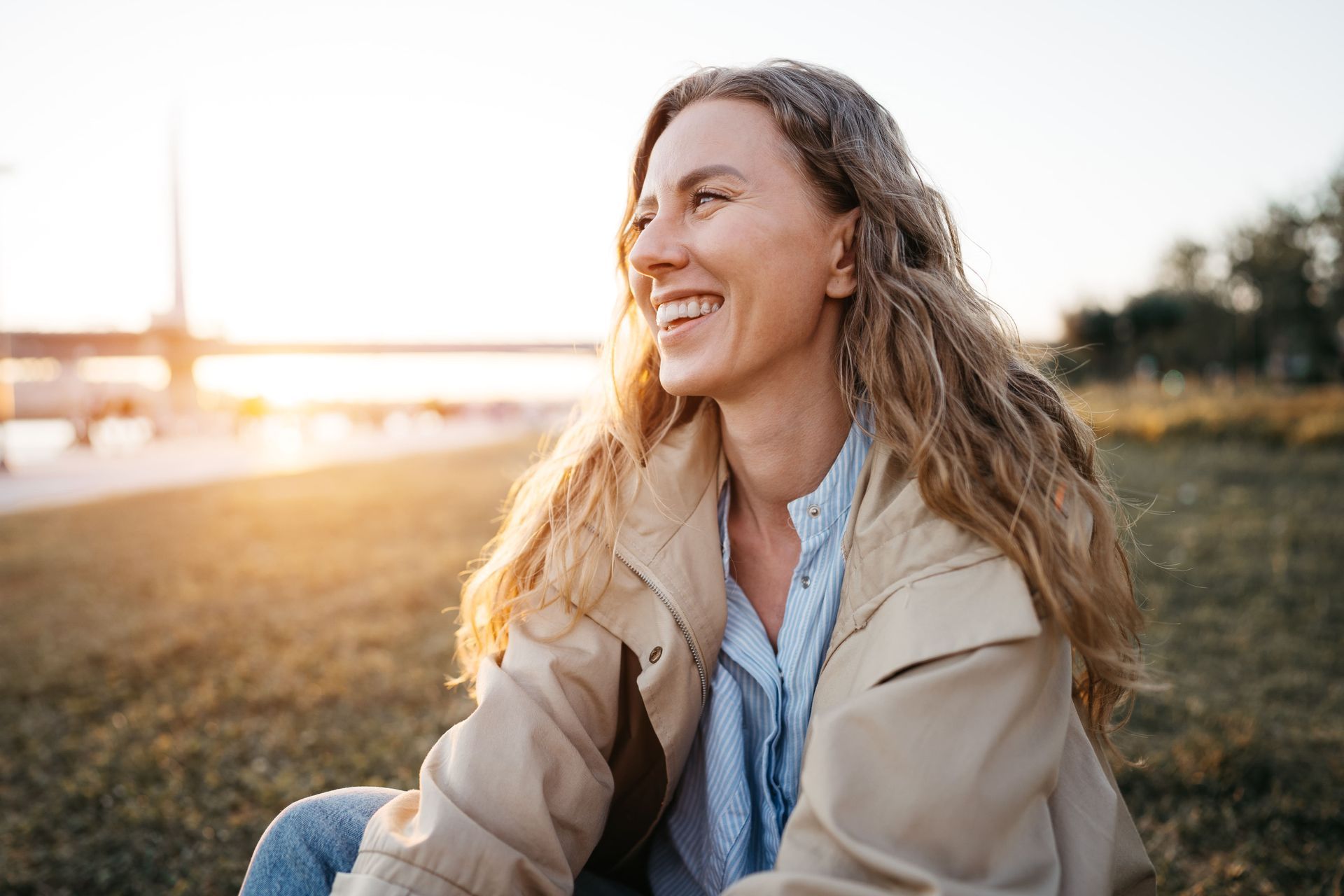 A woman is sitting on the grass and smiling.