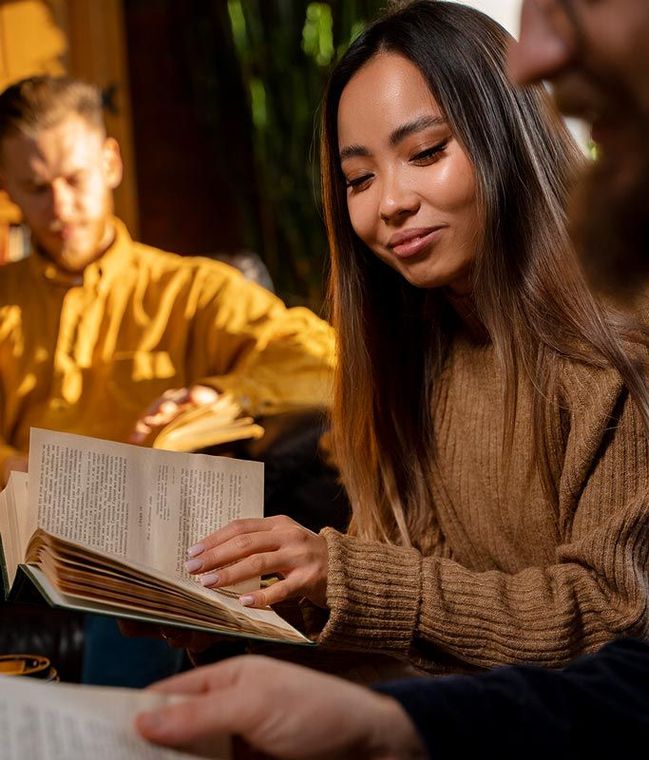 A woman is sitting at a table reading a book.