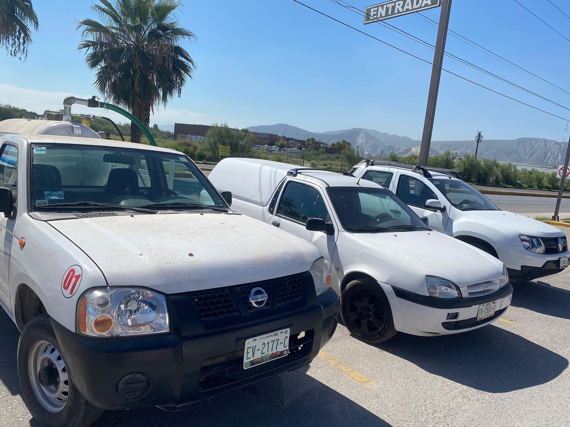 Tres camiones blancos están estacionados uno al lado del otro en un estacionamiento.icon