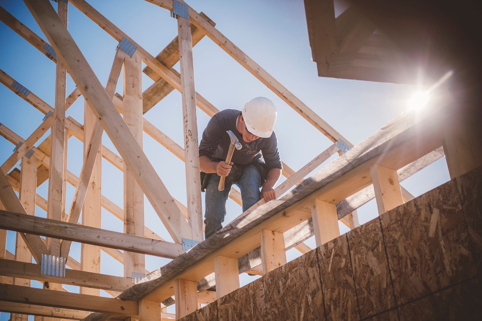 Construction worker hammering wood on a roof frame. Sunny day.