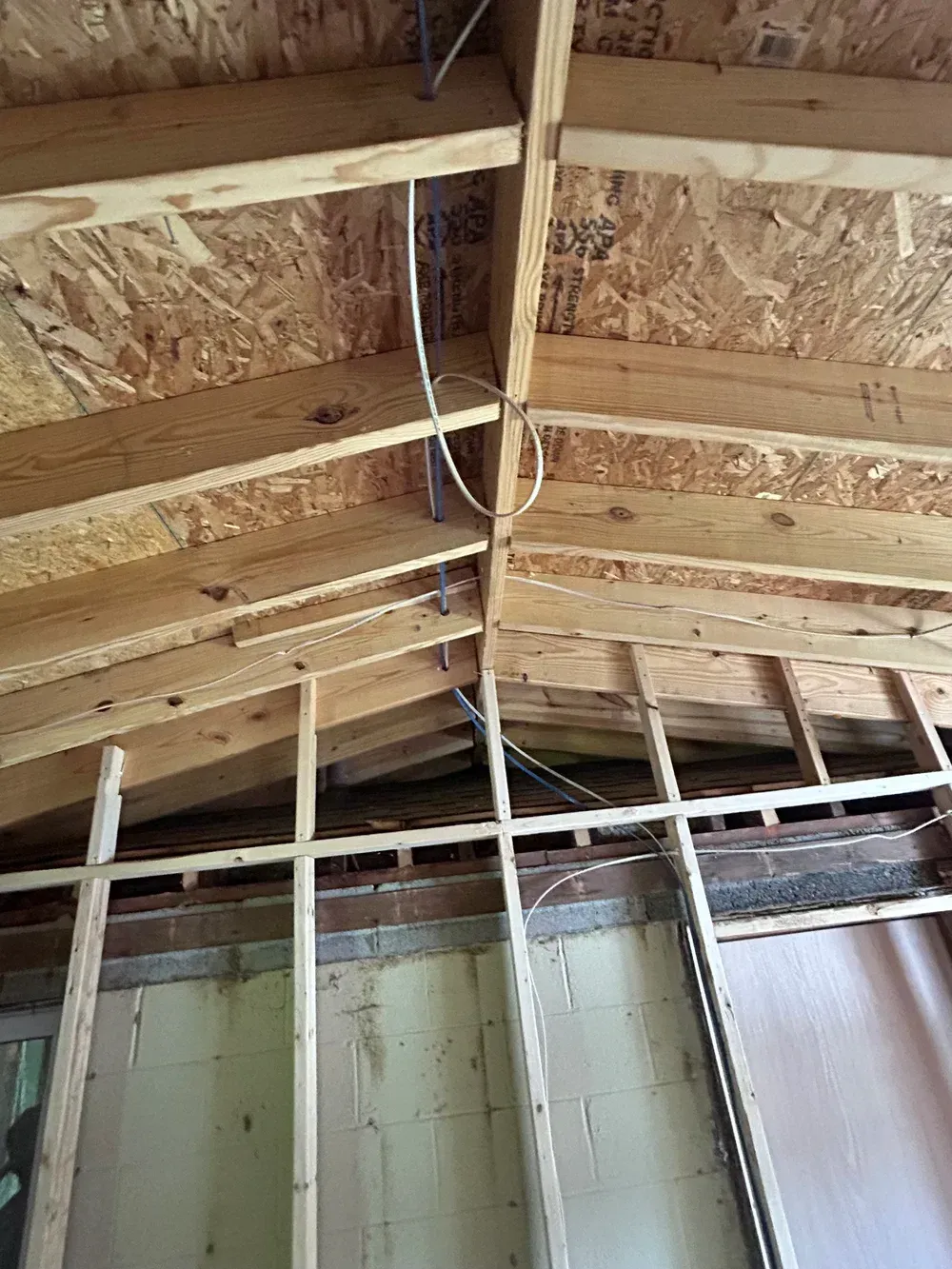 Wood-framed ceiling and wall, with visible electrical wiring against a neutral-colored background.