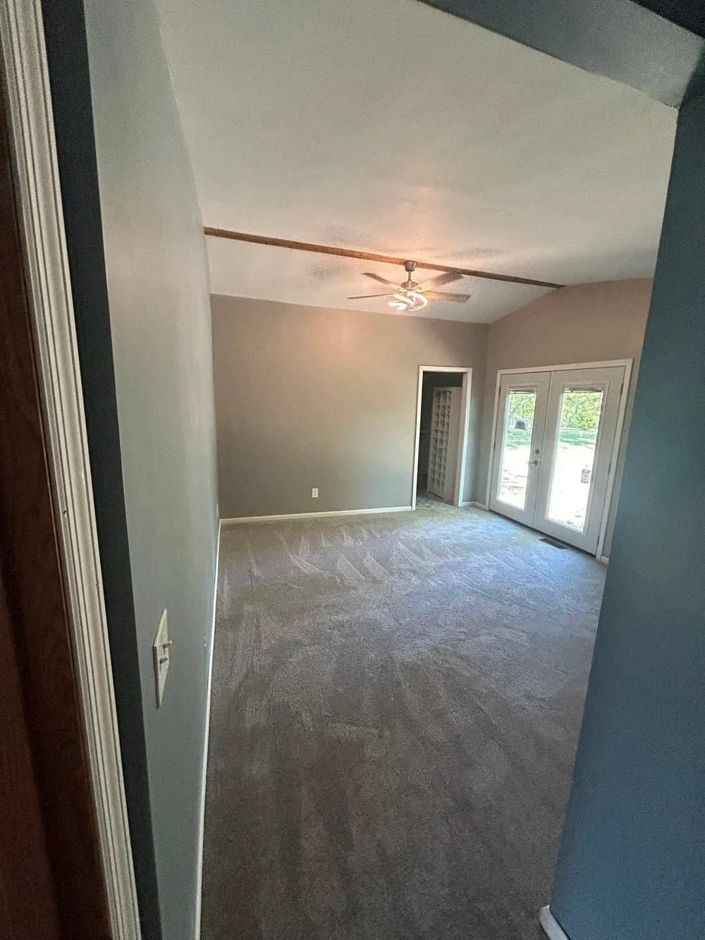 Living room with gray walls, carpet, and French doors.