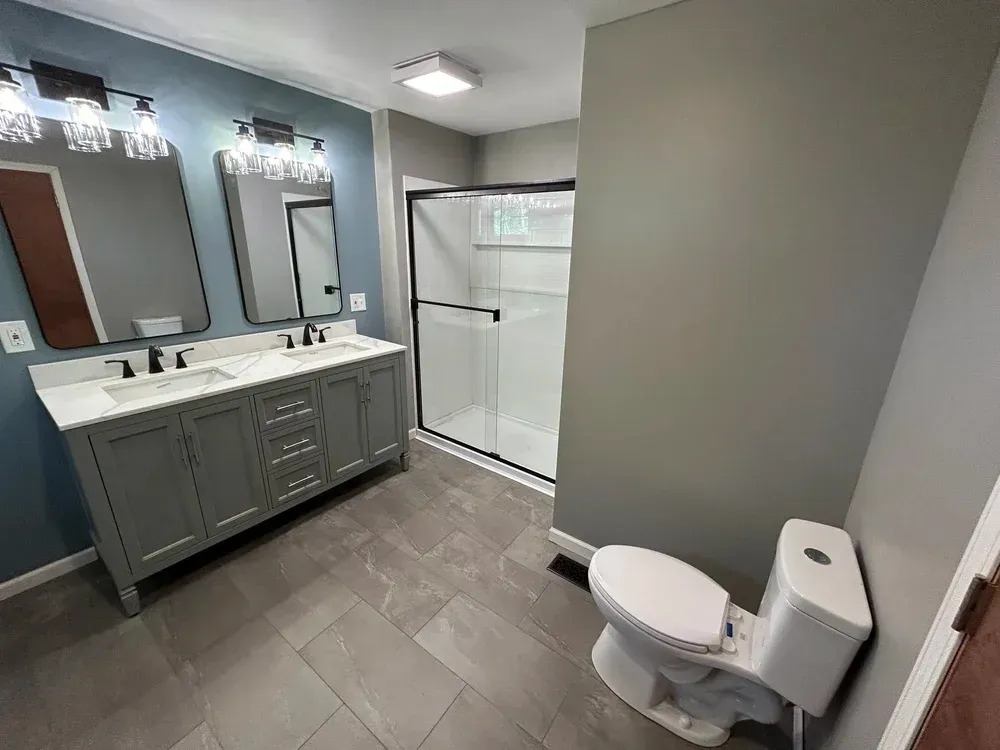 Modern bathroom with gray vanity, blue walls, and a white shower.