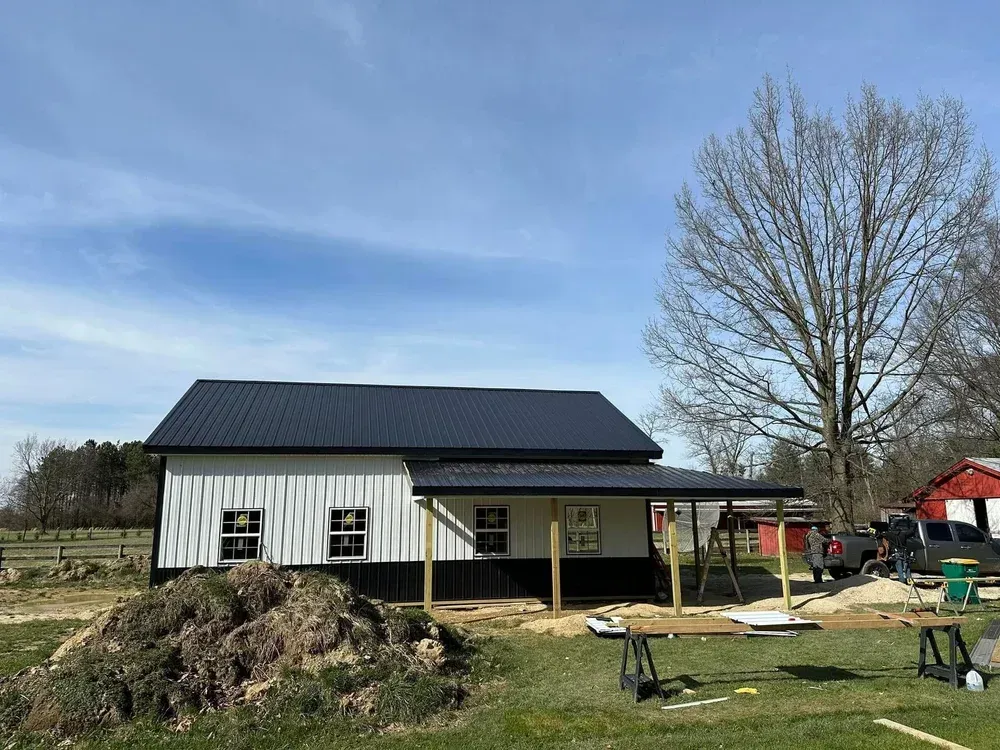 Black and white building with a dark roof under construction. A porch is being built.