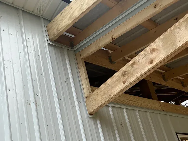 Metal building corner with wooden beams and open space.