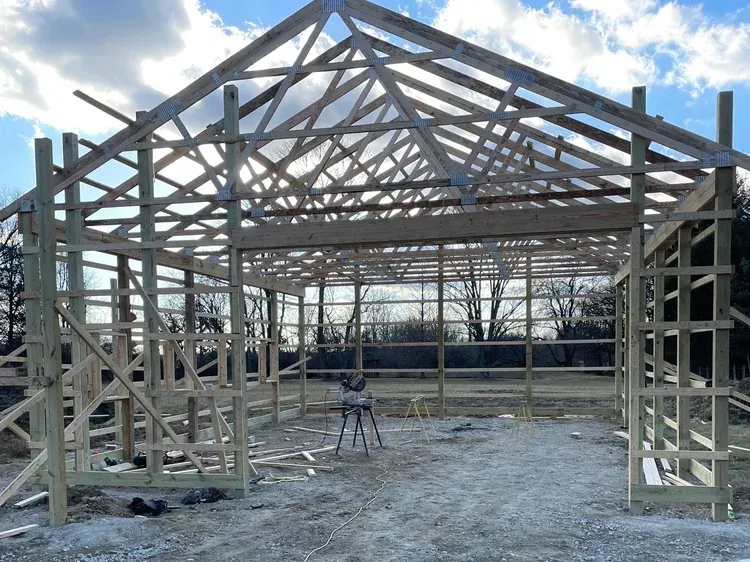 Wooden frame of a barn under construction; open-air, sunny day.