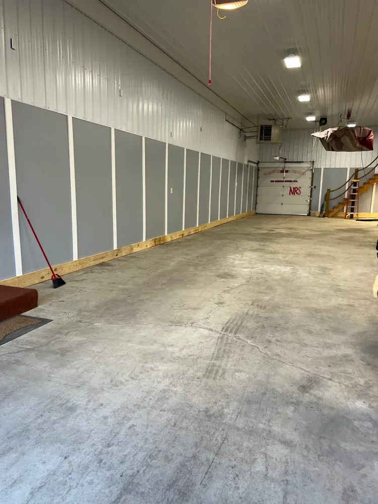 Empty garage with gray concrete floor, white and gray walls, and a closed garage door.