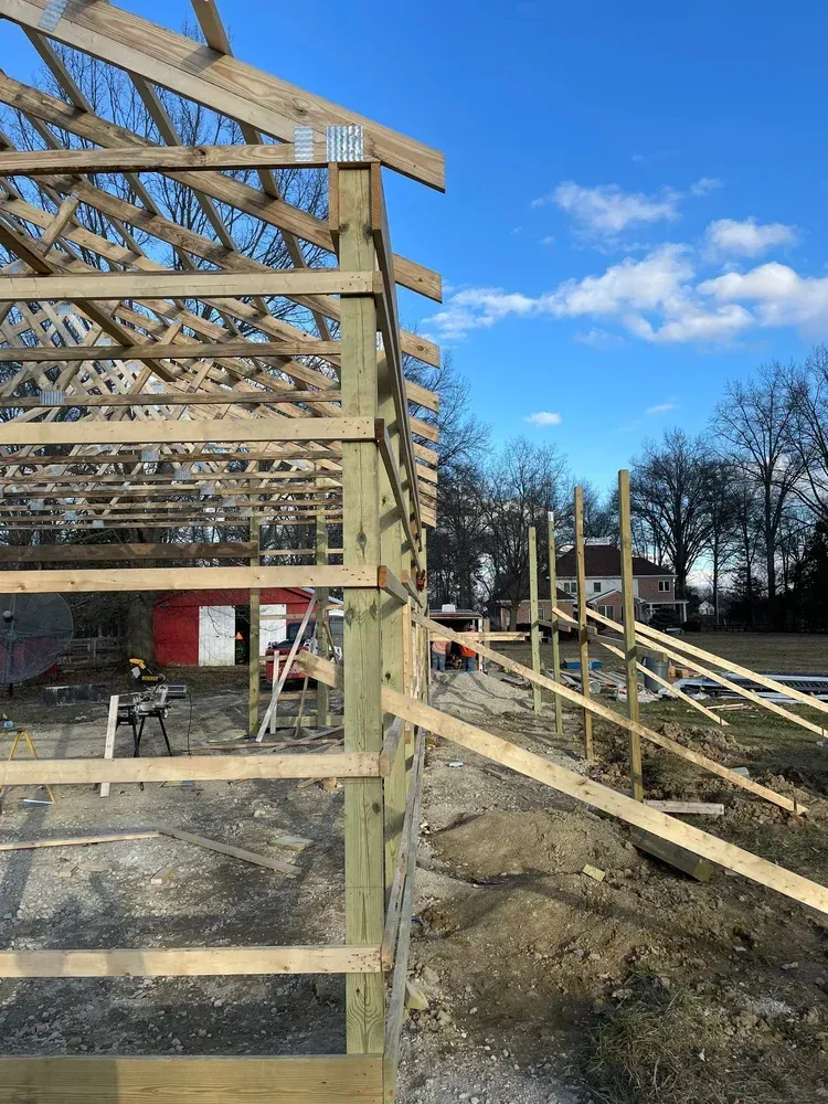 Construction site: wood frame building under construction, blue sky, workers, and tools.