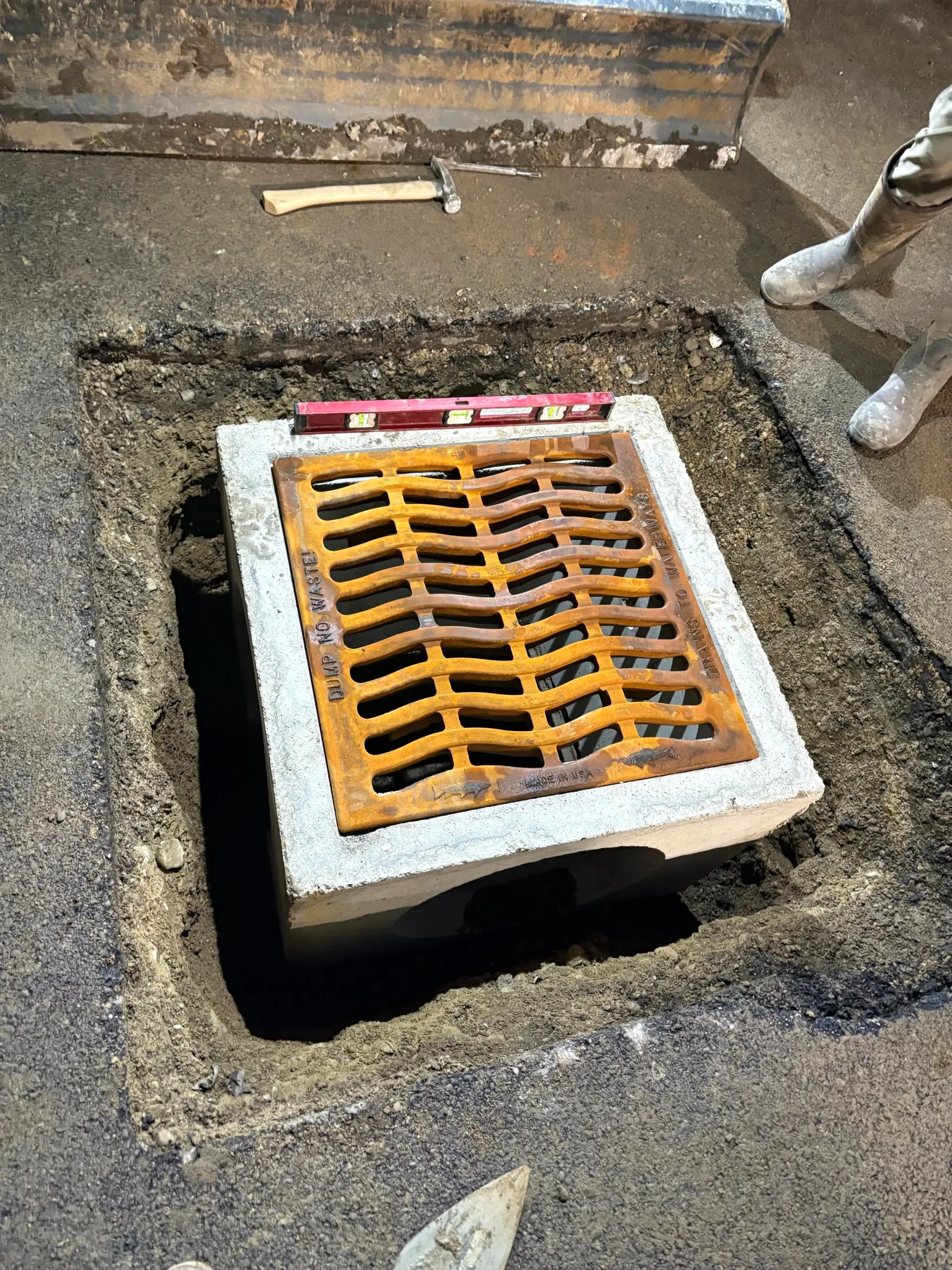 Open drain in asphalt; rusty grate, level on top.