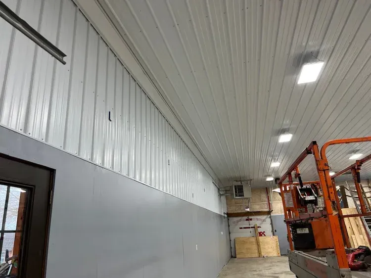 Interior view of a white metal-walled building with grey painted lower walls, and an orange lift.