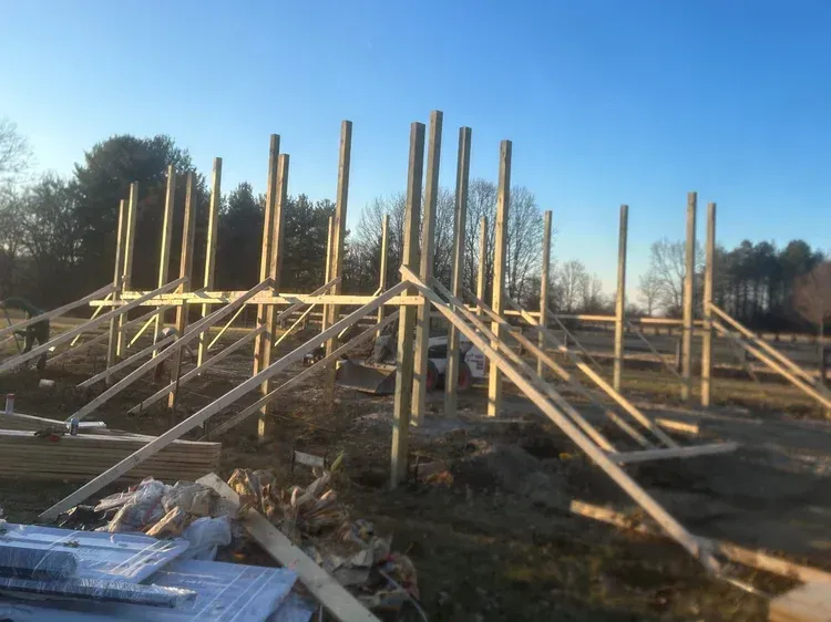 Wooden framework of a building under construction against a clear blue sky.