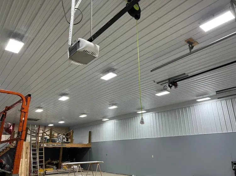 Garage interior with overhead door opener, fluorescent lights, and a lift.