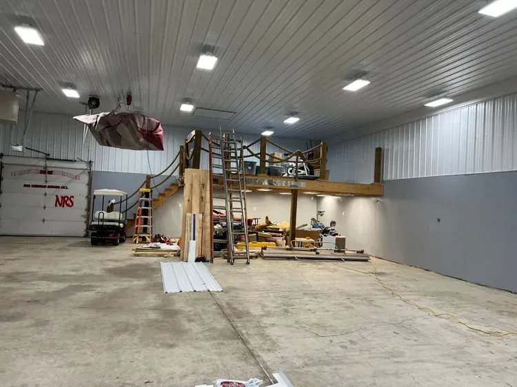 Large open room with a mezzanine under construction, overhead bag suspended.