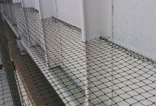 Black safety netting covers a raised platform. White walls and vertical supports create a walkway.