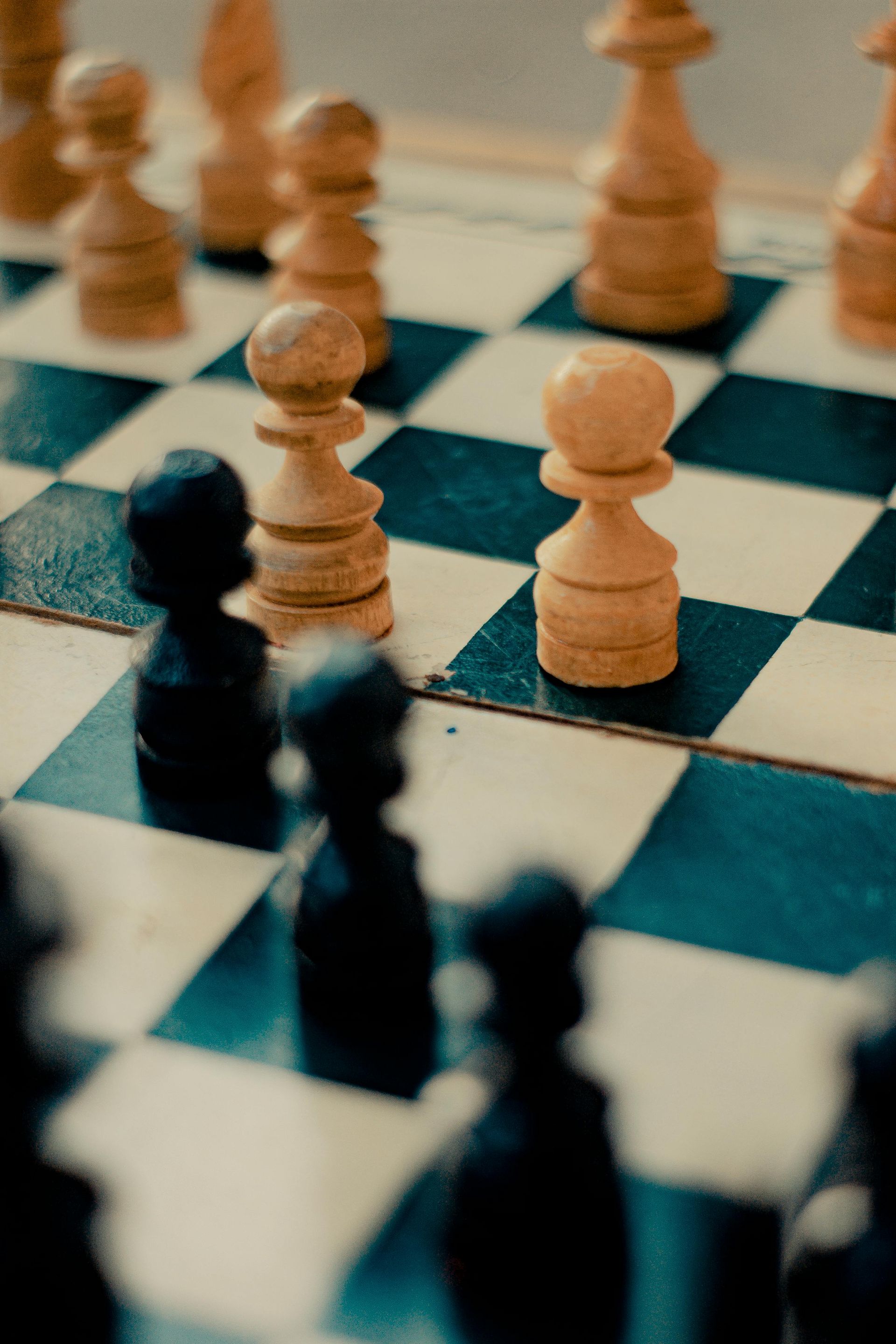 Chessboard with white and black pieces, two white pawns facing black pawns.