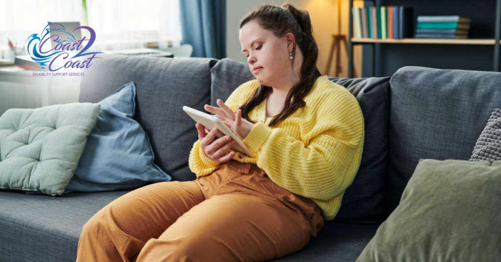 A Woman Is Sitting on A Couch Using a Tablet — Coast 2 Coast Disability Support Services in Taree, NSW