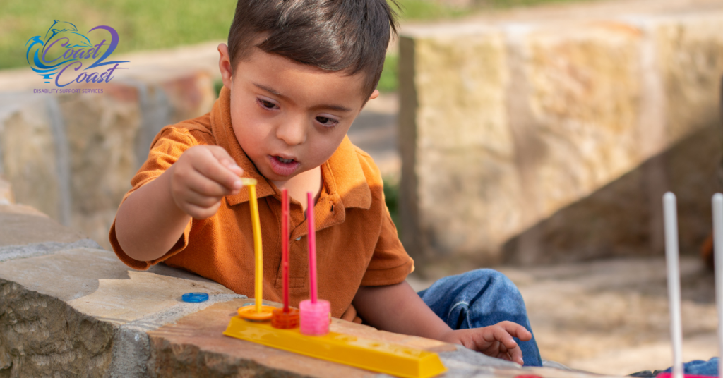 A Young Boy Is Sitting on A Rock Playing With A Toy — Coast 2 Coast Disability Support Services in Taree, NSW