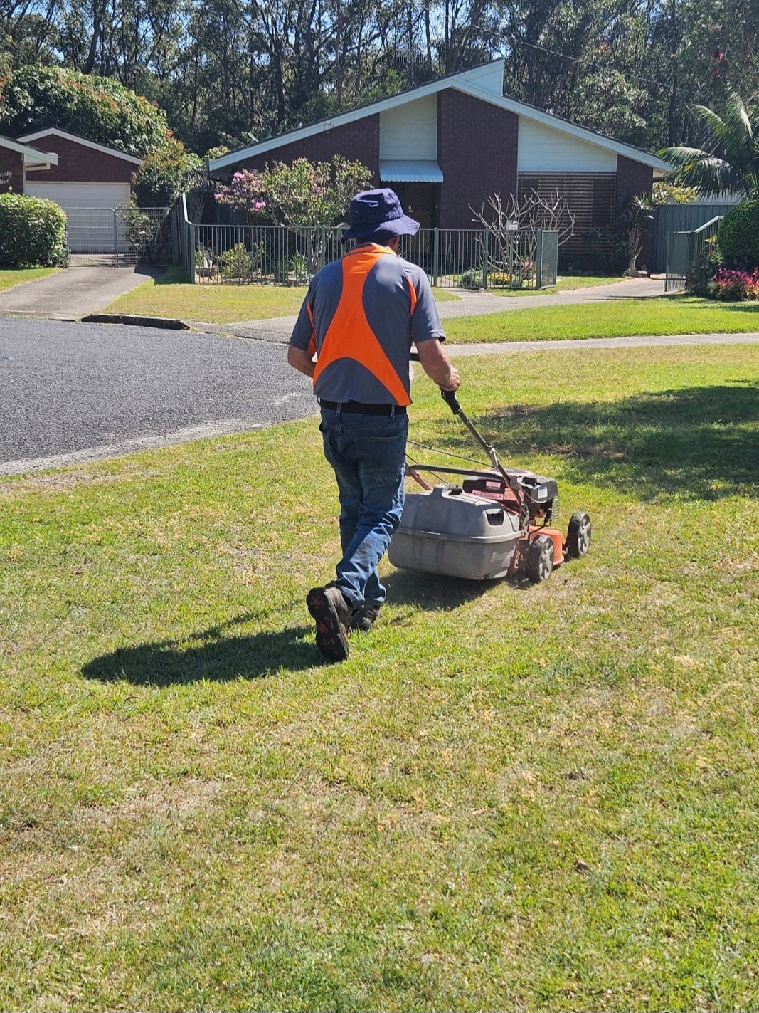 A Man Is Raking Leaves in His Backyard — Coast 2 Coast Disability Support Services in Taree, NSW