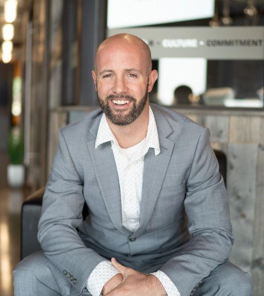 A woman is sitting at a desk with a laptop and a vase of flowers.