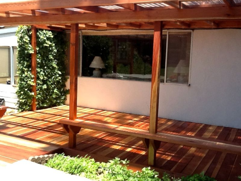 light wood pergola on back patio with bench seating