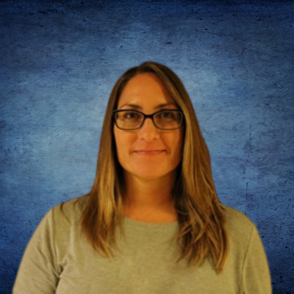 A woman wearing glasses and a grey shirt stands in front of a blue background