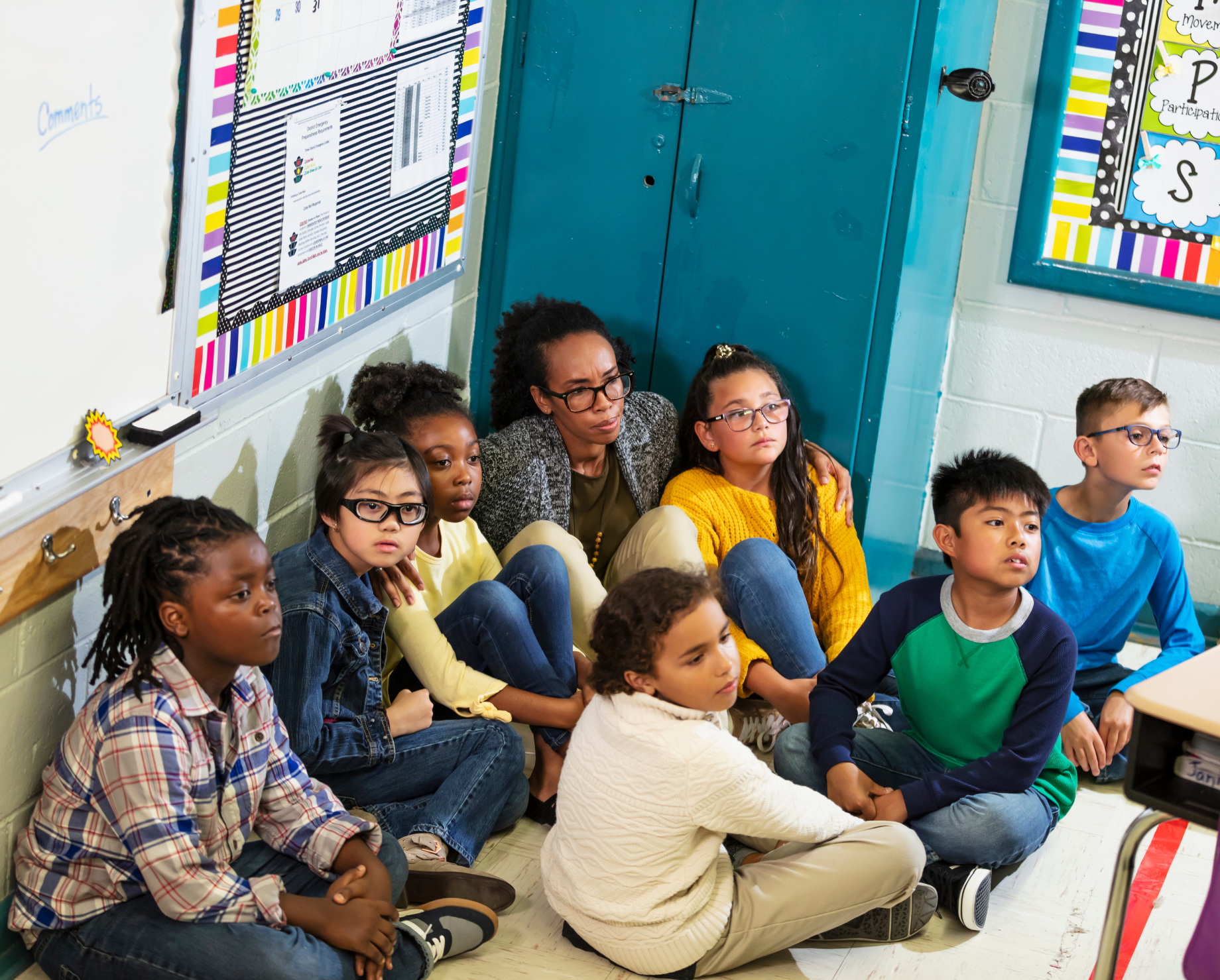 A group of children are sitting on the floor in a classroom.