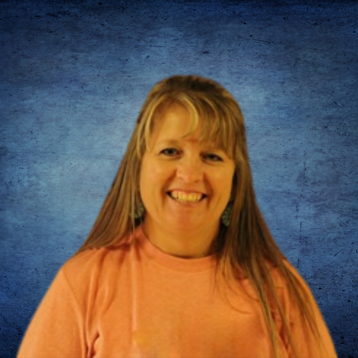 A woman in an orange shirt is smiling in front of a blue background