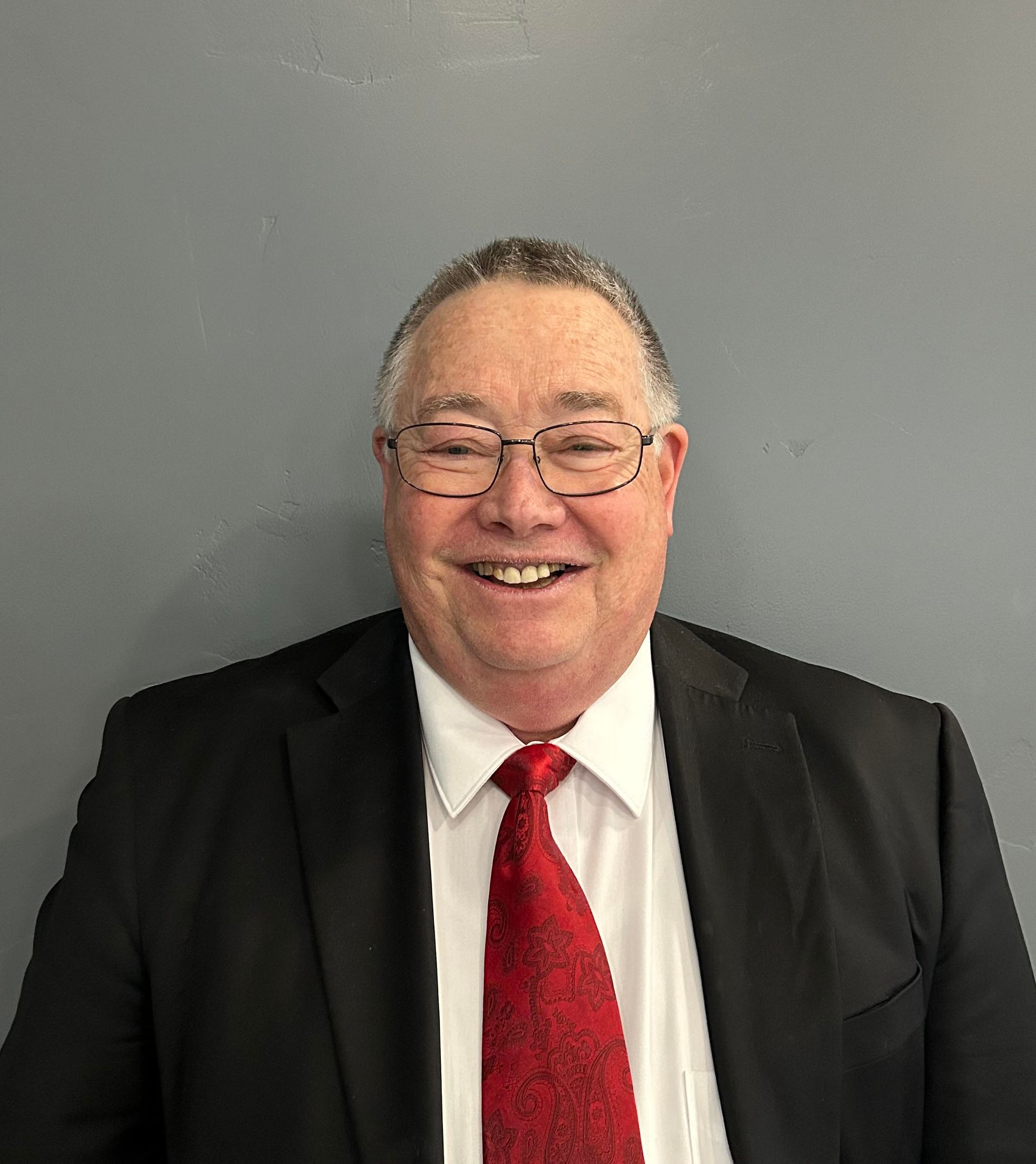 A man in a suit and tie is smiling for the camera.