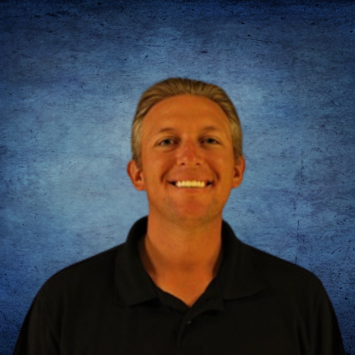 A man in a black shirt is smiling in front of a blue background