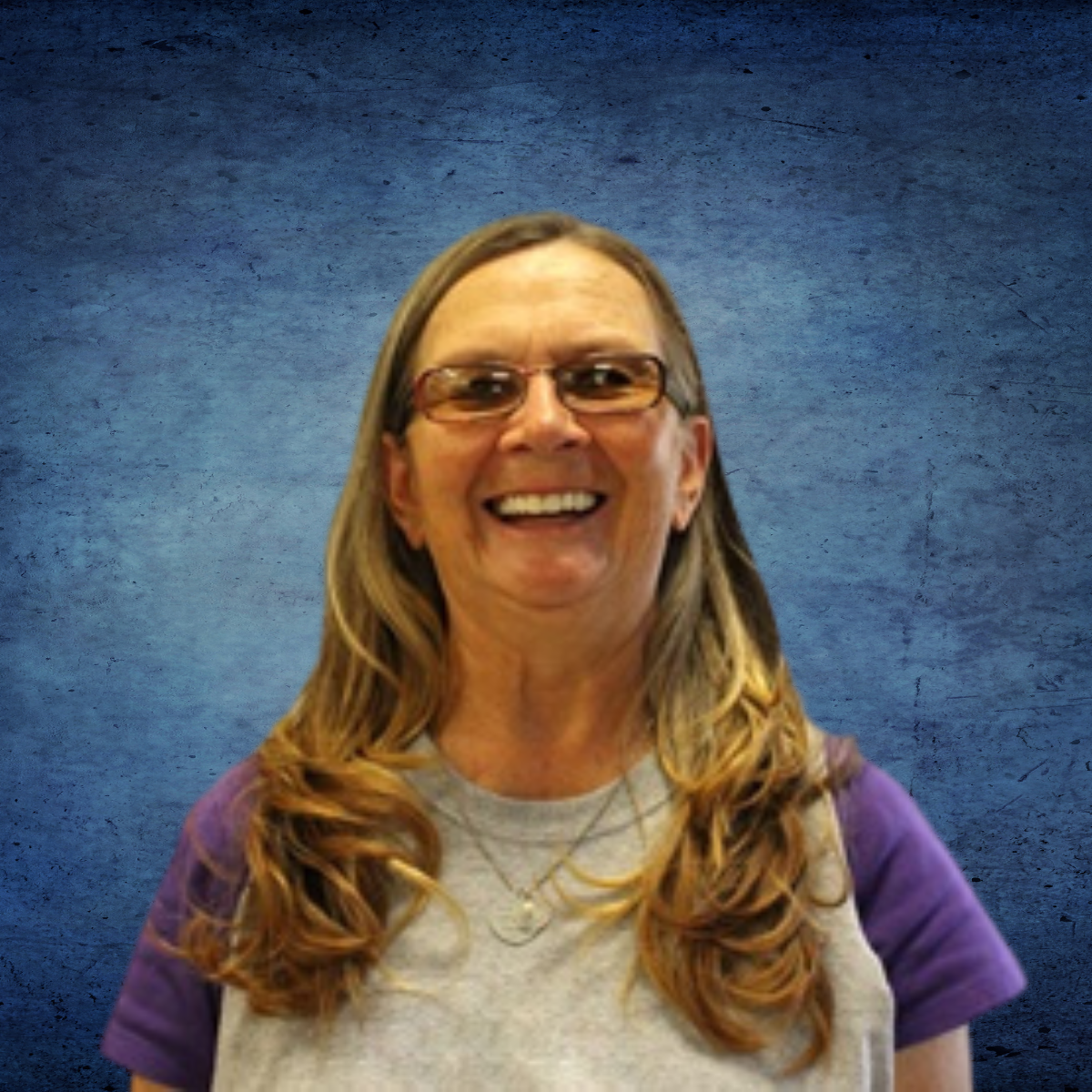 A woman wearing glasses and a purple shirt smiles for the camera