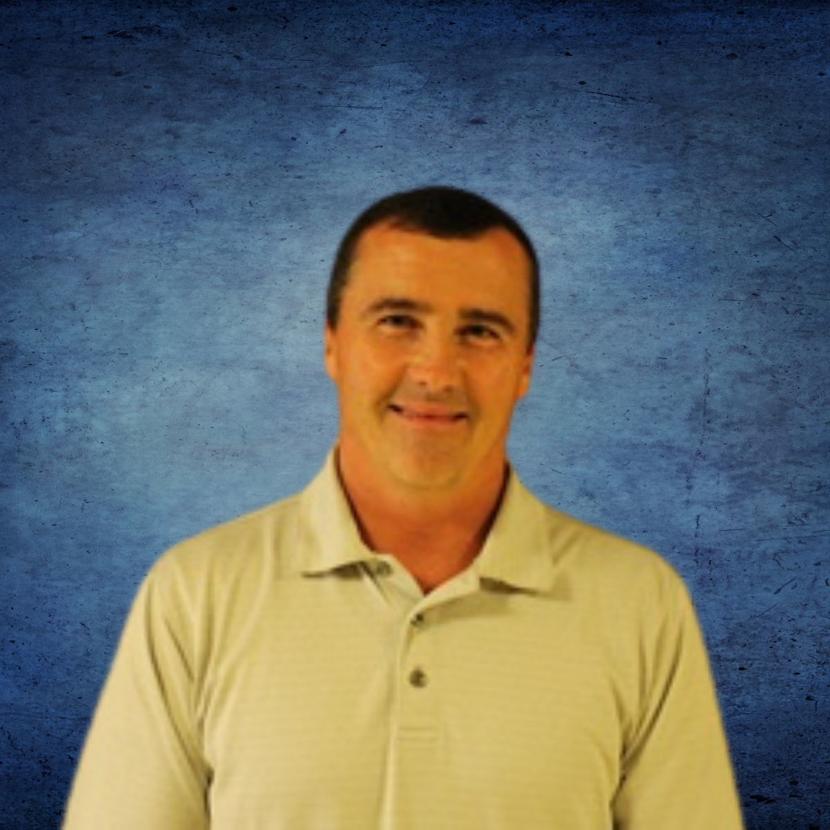 A man in a white shirt is smiling in front of a blue background