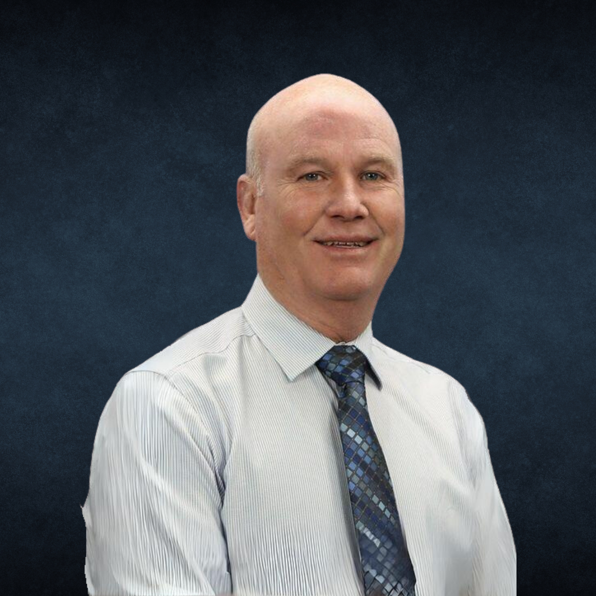 A bald man wearing a white shirt and tie smiles for the camera