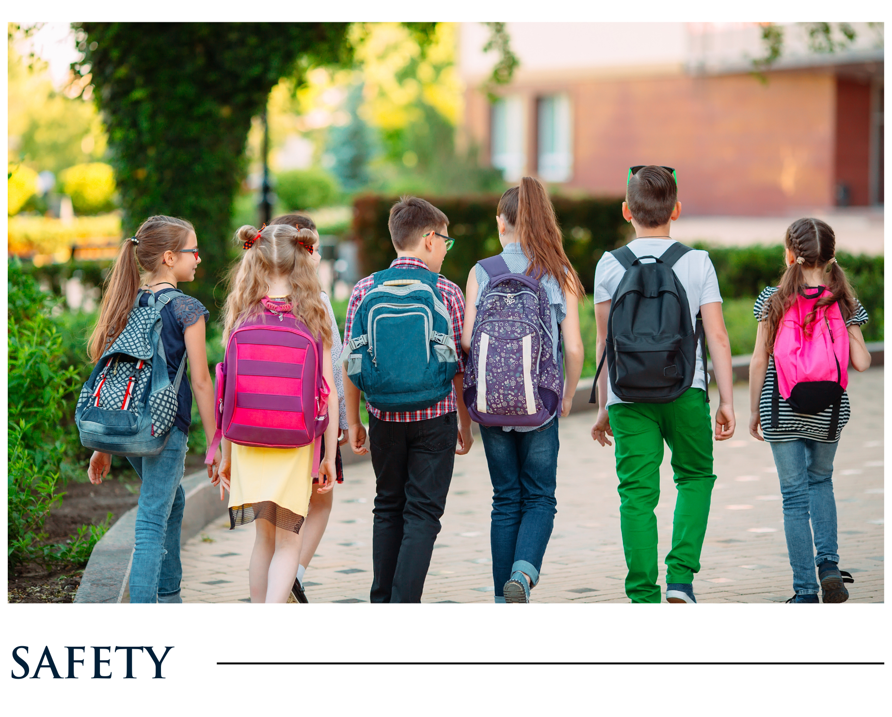 A group of children with backpacks are walking down a sidewalk.
