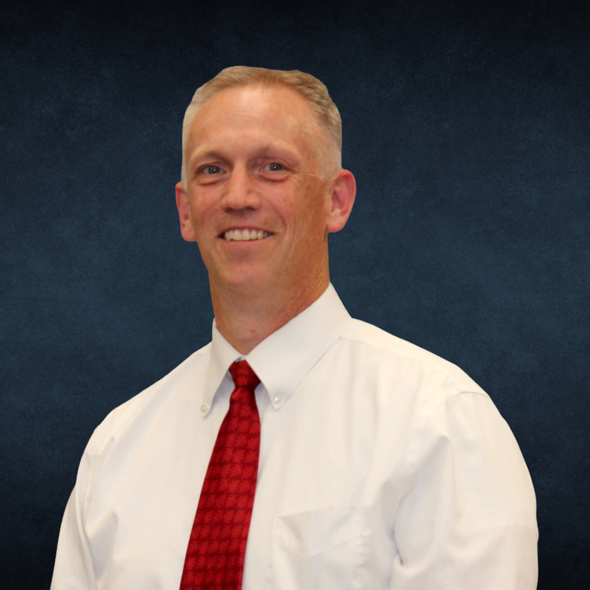 A man in a white shirt and red tie smiles for the camera