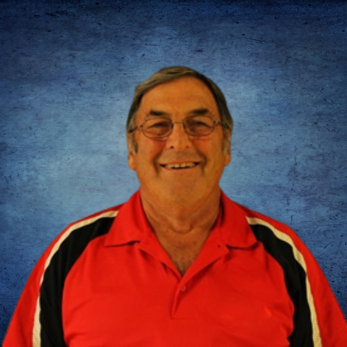 A man wearing glasses and a red shirt smiles for the camera