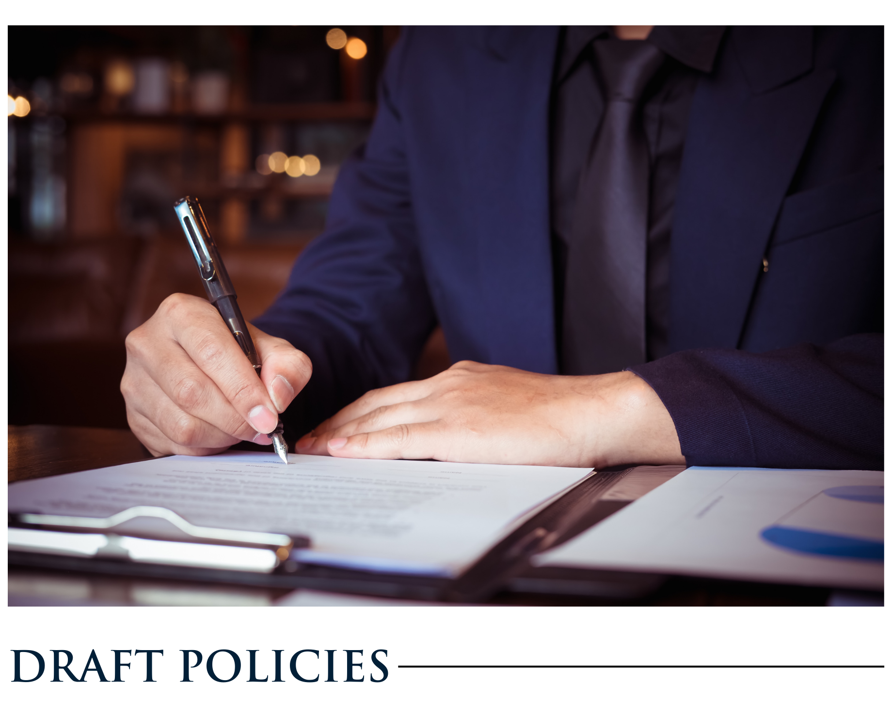 A man in a suit and tie is writing on a piece of paper.