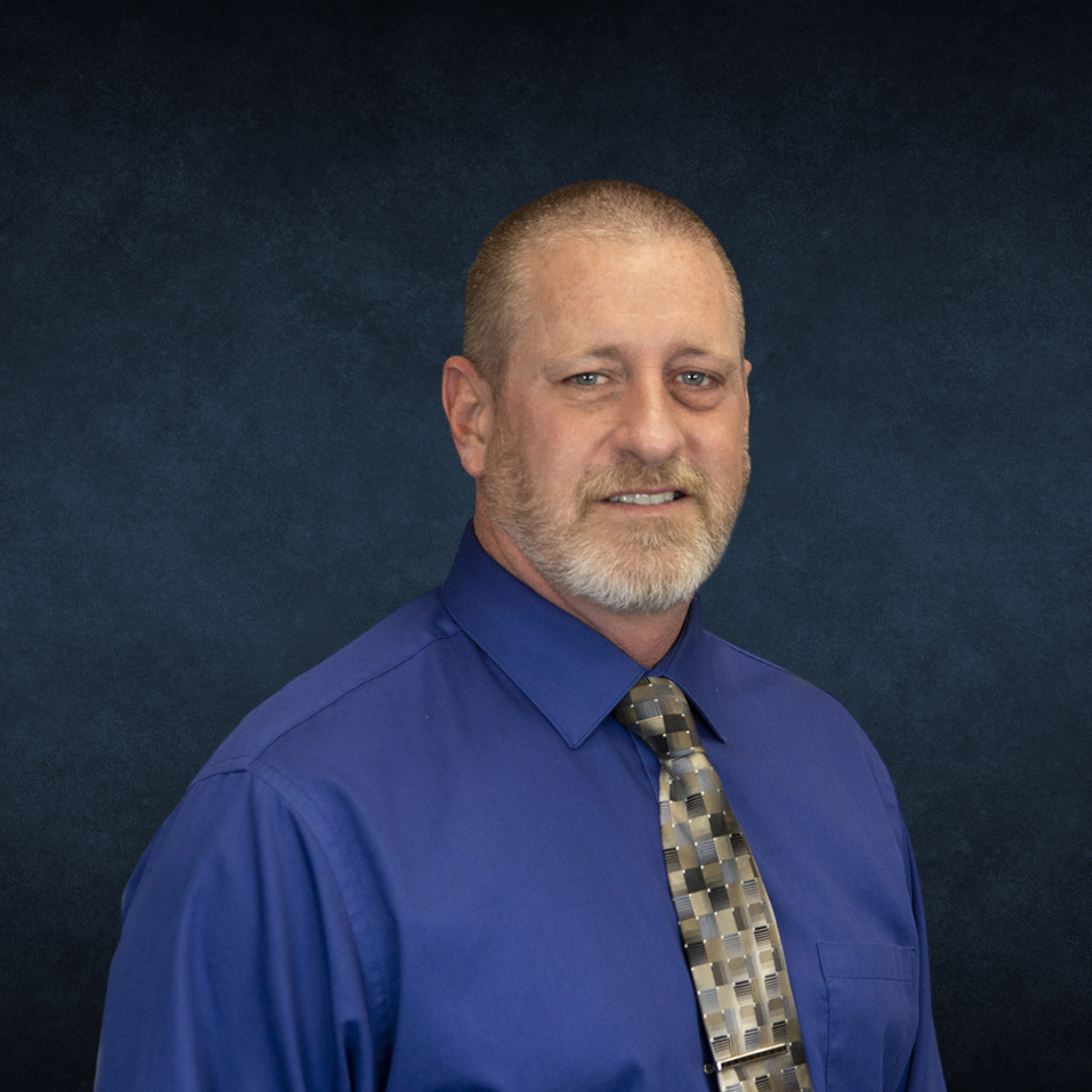 A man with a beard is wearing a blue shirt and tie.