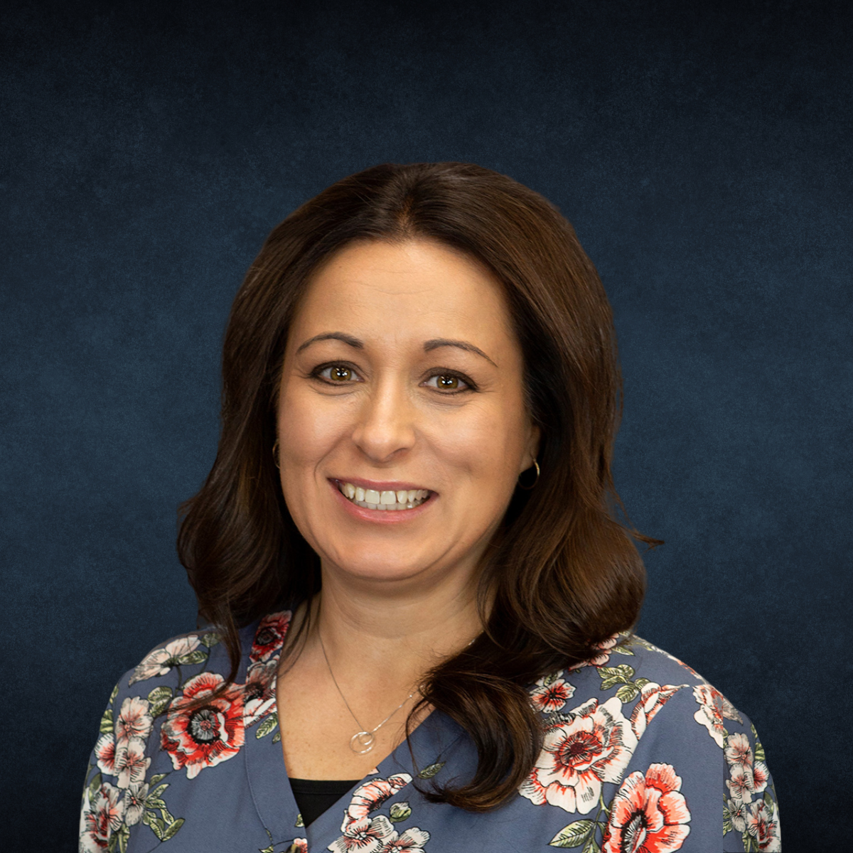 A woman in a floral shirt is smiling for the camera.