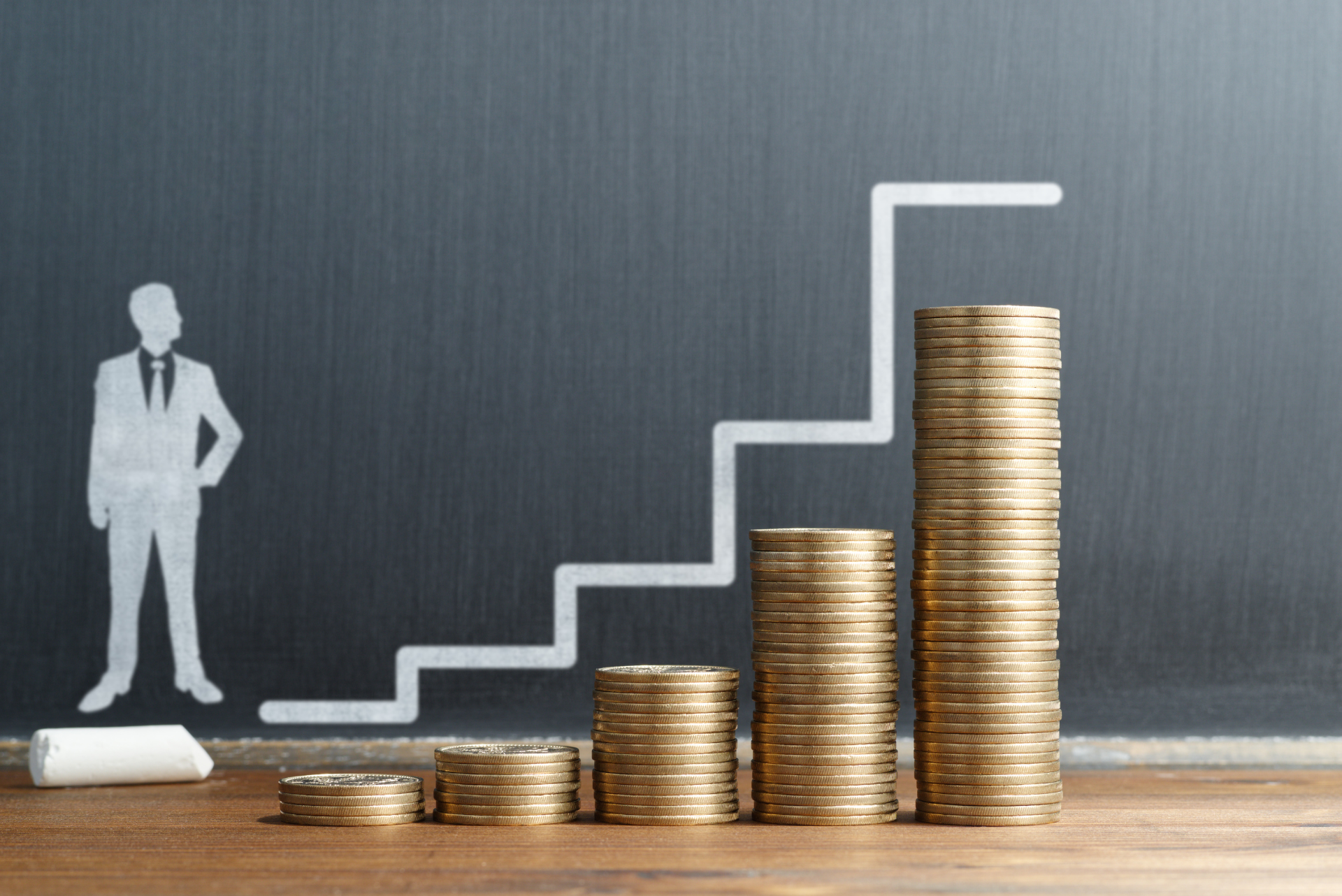A man in a suit is standing next to a staircase made of coins.
