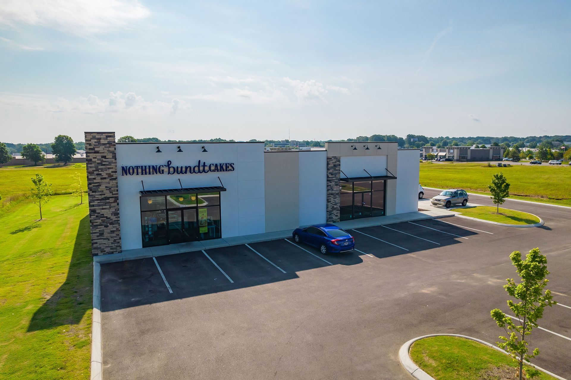 Modern building with "smith & bundt" signage, blue car parked, asphalt lot, green grass.