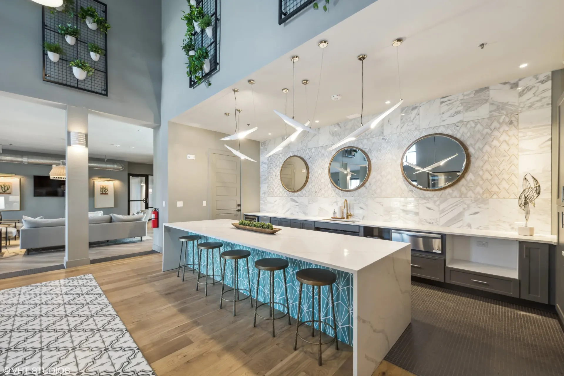 Modern community kitchen with marble island, bar stools, and geometric tile accents.